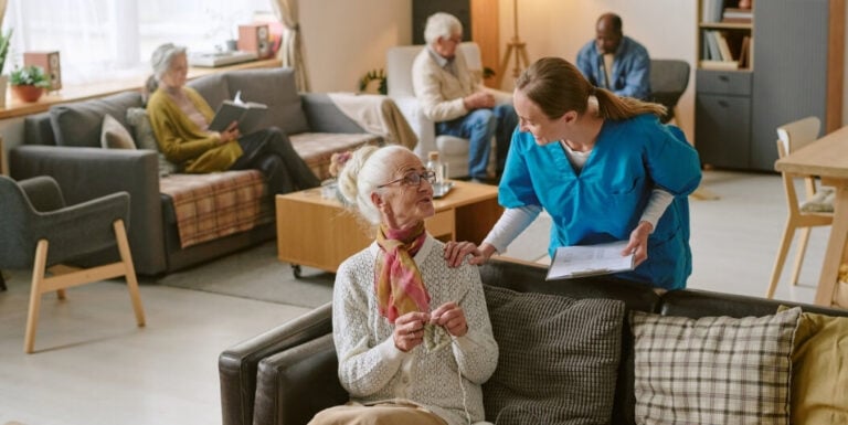 Female Nurse with Senior Woman in Common Area at Memory Care Facility