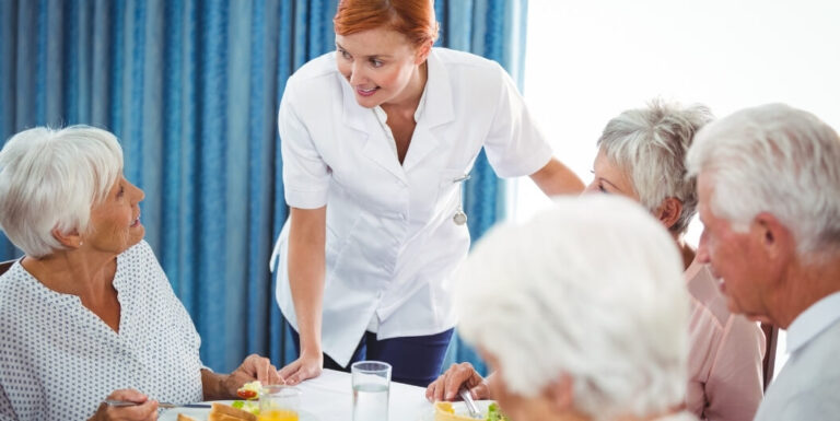 Female Nurse Serving Meal to Elderly Residents at Memory Care Facility