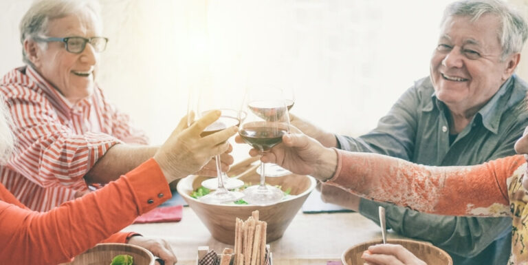 Group of Seniors Toasting Wine Glasses at a Dining Table at a Memory Care Facility